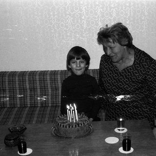 A woman and child blowing out birthday cake candles together.