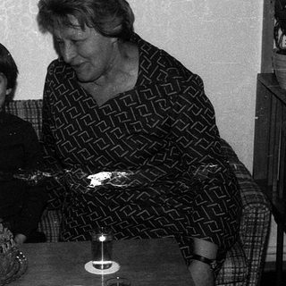A woman and child blowing out birthday cake candles together.