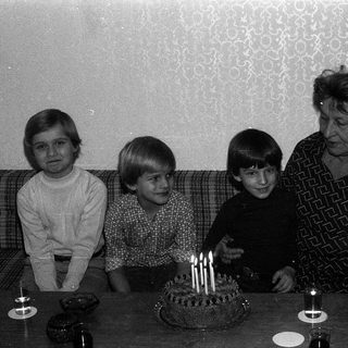 Family celebrating birthday with lit candles on cake.