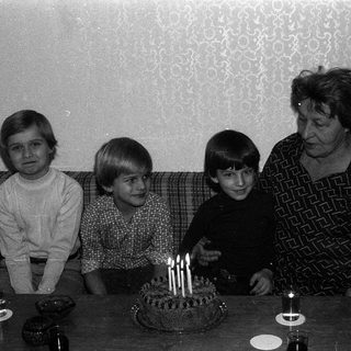 Family celebrating birthday with lit candles on cake.