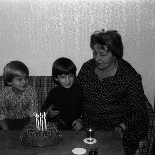 Family celebrating birthday with lit candles on cake.