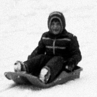 Child sledding down snow-covered hill.