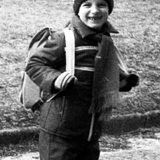 Child holding snowball in winter park.