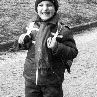 Child smiling outdoors in winter attire.
