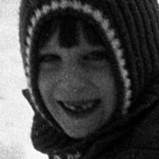 Child joyfully sledding down snow-covered slope.