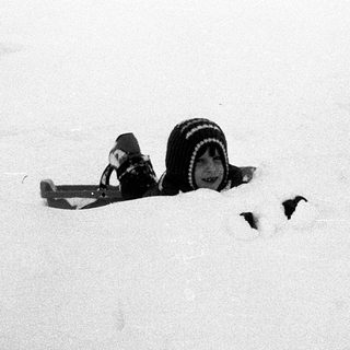 Snowboard partially buried in snow.