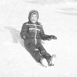 Person sledding down snow-covered slope.