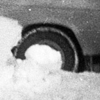 Children sledding down snow-covered hill.