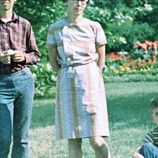 Three people posing outdoors in a park setting.