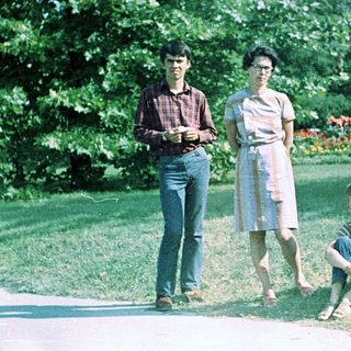 Three people posing outdoors in a park setting.