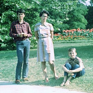 Three people posing outdoors in a park setting.