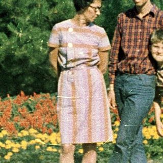 Family posing outdoors in colorful park flowers.
