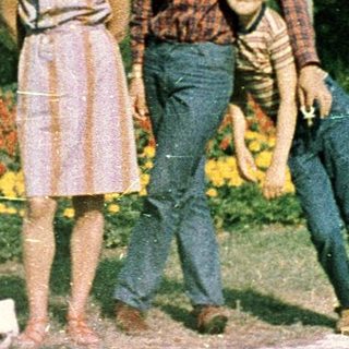 Family posing outdoors in colorful park flowers.