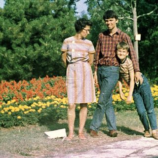 Family posing outdoors in colorful park flowers.