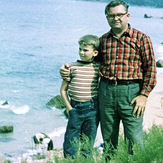 Father and son posing by seaside.