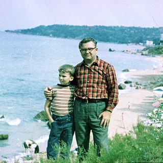 Father and son posing by seaside.