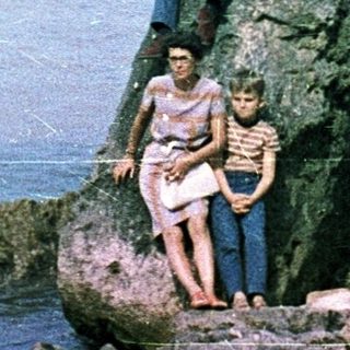 Family posing on rocky seaside ledge near ocean.