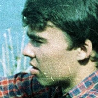 Young man sitting by water, deep in thought.