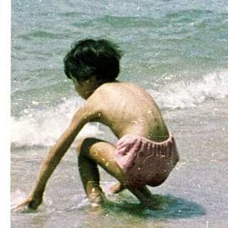 Busy beach scene with children playing in shallow water.