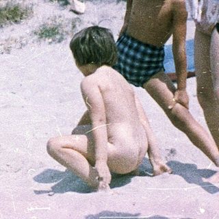Children playing in shallow sand near water.