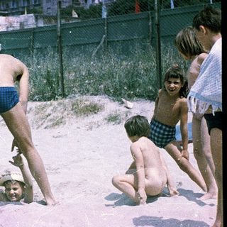 Children playing in shallow sand near water.