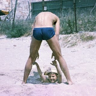 Children playing in shallow sand near water.