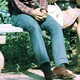 Three people sitting on bench outdoors, smiling.