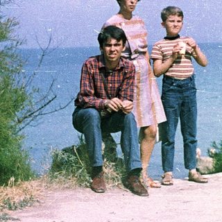 Family posing near coastal cliffside path.