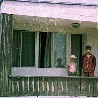 Family posing on porch of vintage mobile home.
