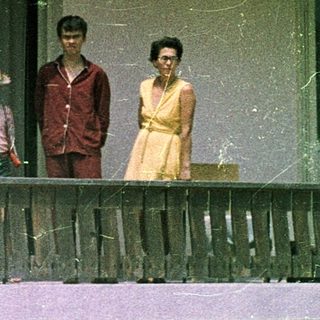 Family posing on porch of vintage mobile home.