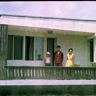 Family posing on porch of vintage mobile home.