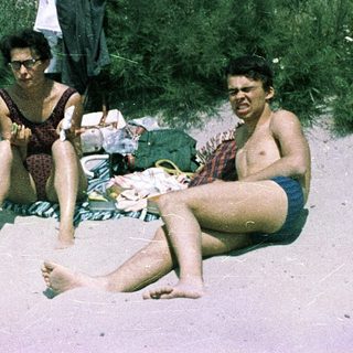 Three people relaxing on beach with surfboards.