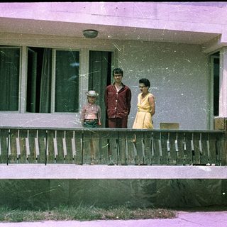 Family posing on porch of older home.