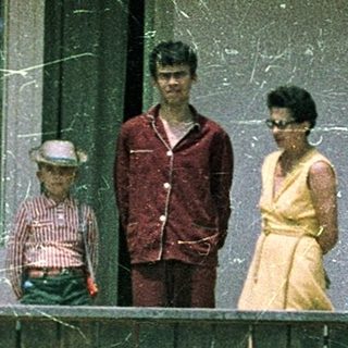 Family posing on porch of older home.