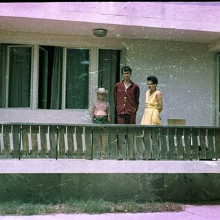 Family posing on porch of older home.