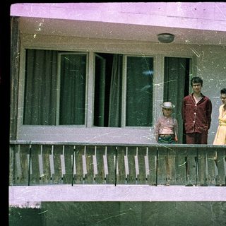 Family posing on porch of older home.