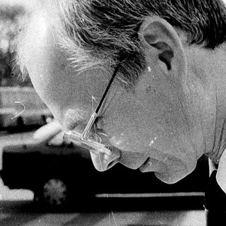 Man examining map with magnifying glass outdoors.