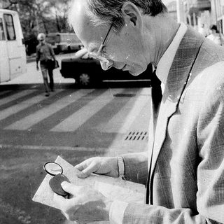 Man examining map with magnifying glass outdoors.