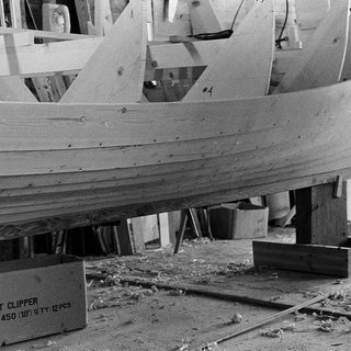 Boat hull under construction with wood planks and bolts.