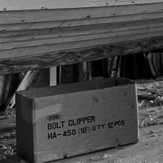 Boat hull under construction with wood planks and bolts.