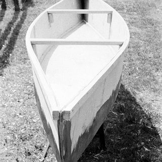 Small wooden boat on dry land.