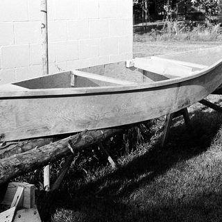 Small wooden boat on supports outdoors.