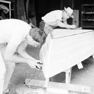 Two men working on boat construction.