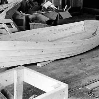 Unfinished wooden boat in workshop under construction.