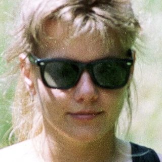 Woman wearing sunglasses, black tank top, outdoors.