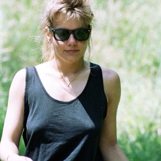 Woman wearing sunglasses, black tank top, outdoors.