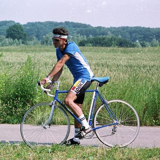 Cyclist riding road bike through green countryside.