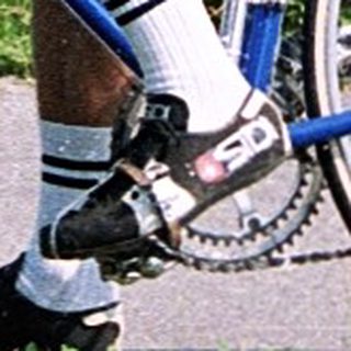 Cyclist riding road bike through green countryside.