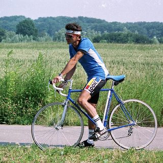 Cyclist riding road bike through green countryside.