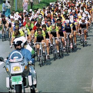 Cyclists racing in a large group on a road.